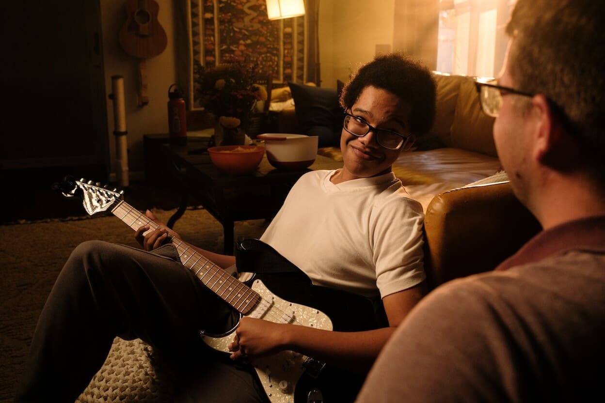 Mentor and mentee sharing guitar lesson in cozy living room