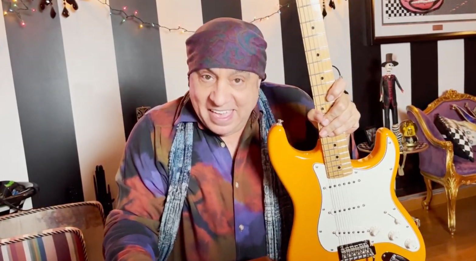 Stevie Van Zandt smiling with signed orange Fender Stratocaster